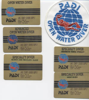 Frame gray white back ground within five SCUBA Diving Certification cards and an Open Water Diver patch from PADI
